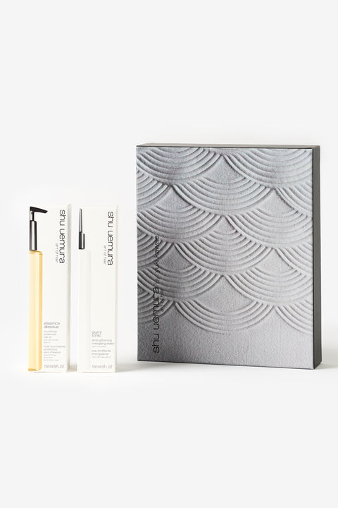 Une boite grise avec les boites pour les produits izumi tonic et essence absolue de shu uemura.