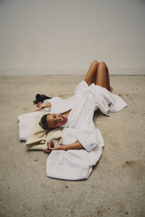 Une femme porte la robe Pinklablonde Atelier et est couchée sur du sable.