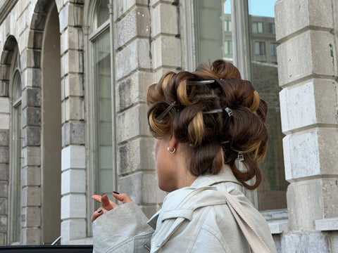 Personne de dos avec cheveux en bigoudis dehors.