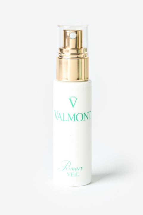 Une bouteille blanche Valmont avec une pompe dorée.