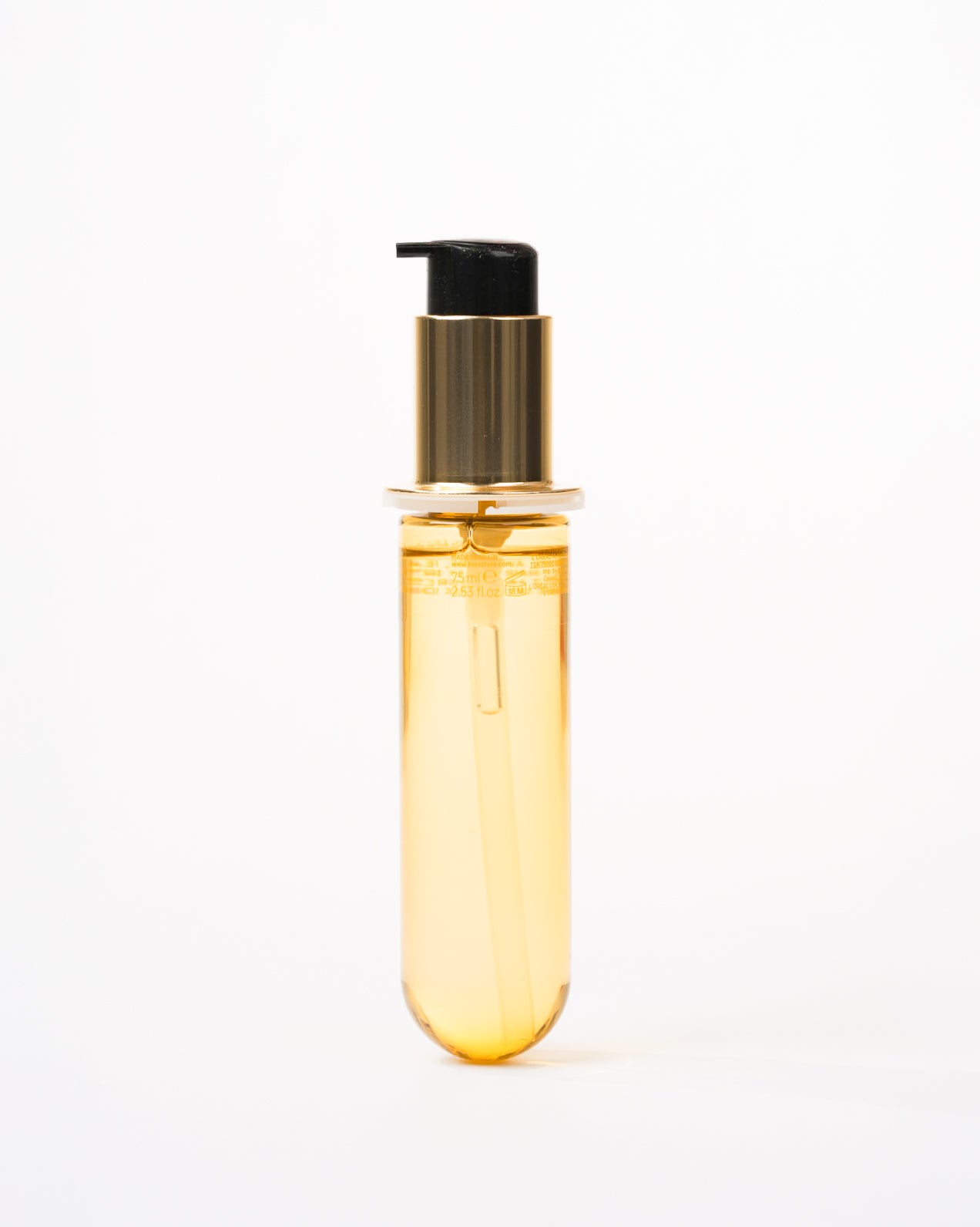 un flacon long et transparent contenant un liquide doré, équipé d’une pompe noire et dorée. Le design est minimaliste, sans étiquette visible, donnant une apparence élégante et épurée.